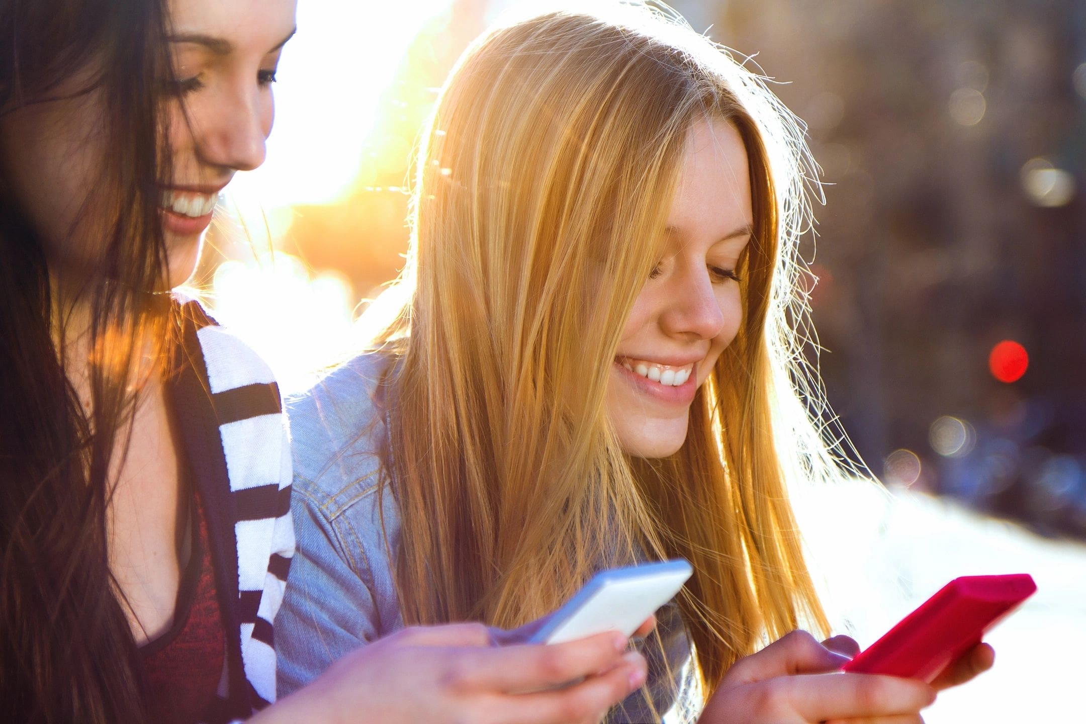 Two girls are looking at their phones.