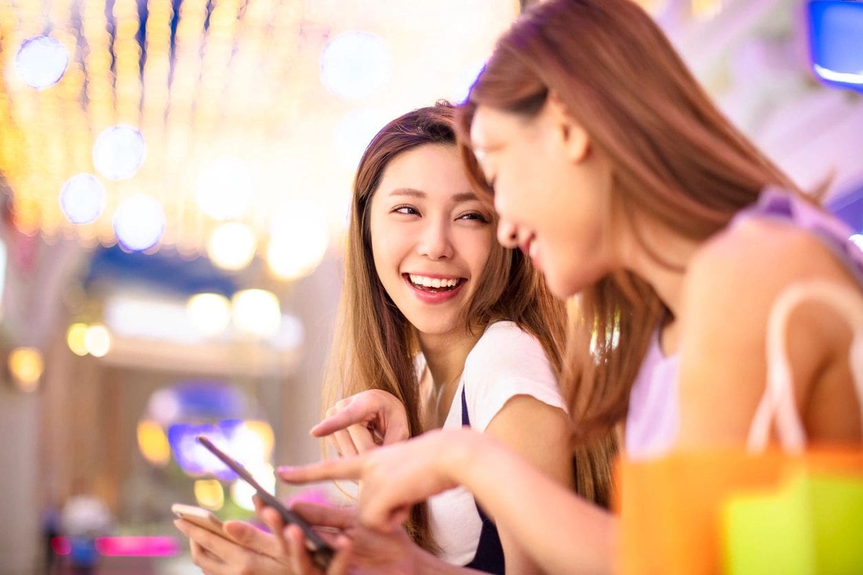 Two women laughing while looking at a phone.